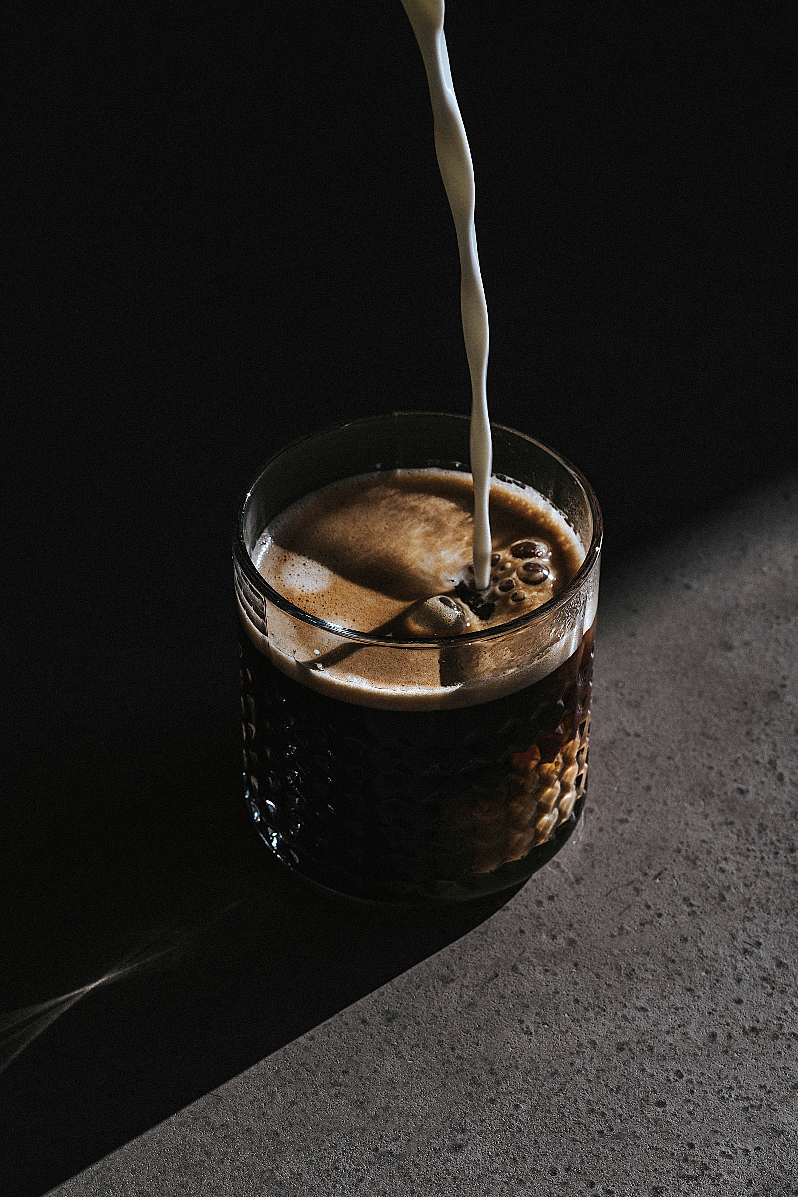 Chiaroscuro — milk poured into espresso in dramatic light
